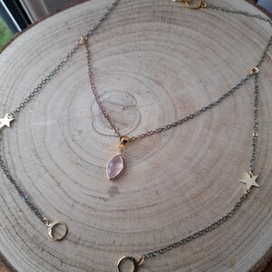 May include: A delicate gold chain necklace with a pink gemstone pendant and star and crescent moon charms.