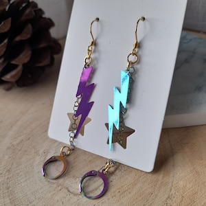 May include: A pair of iridescent earrings with lightning bolt charms. One earring is purple and the other is blue.