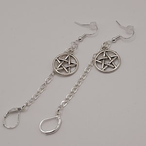 May include: Silver dangle earrings with a pentagram charm on each earring. The earrings have a hook fastening.