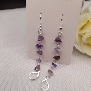 May include: A pair of silver dangle earrings with amethyst gemstone beads. The earrings are approximately 2 inches long and feature a hook closure.