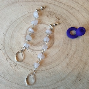 May include: A pair of silver earrings with a chain of white gemstone beads. The earrings have a hook fastening.