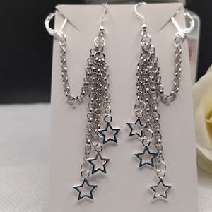 May include: Silver dangle earrings with multiple chains and star charms.