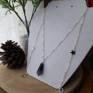 May include: A silver chain necklace with a purple amethyst pendant and two silver star charms.
