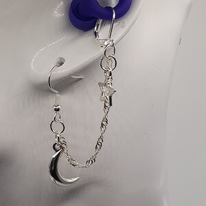 This image shows the moon and star loop earplug earrings being worn with the loop earplug in the ear and showing the drape of the chain.