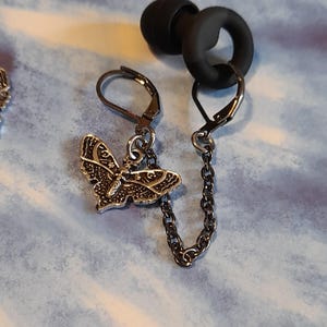 May include: A white ceramic mug with a black handle and the text "But first, coffee" in a black, handwritten-style font. The mug is on a white surface.