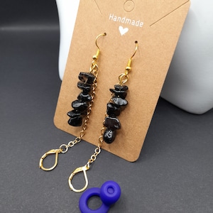 Könnte beinhalten: Schwarze Edelsteinohrringe mit goldenen Ketten und Haken. Die Ohrringe sind handgefertigt und haben eine braune Karte mit dem Wort "Handmade" darauf.