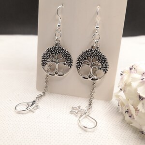 May include: Silver tone tree of life earrings with a dangling star and a drop charm on each earring.
