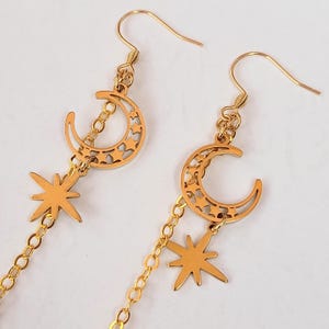 This image shows a more detailed close up of the crescent moon and north star charms attached to the earring hooks.
