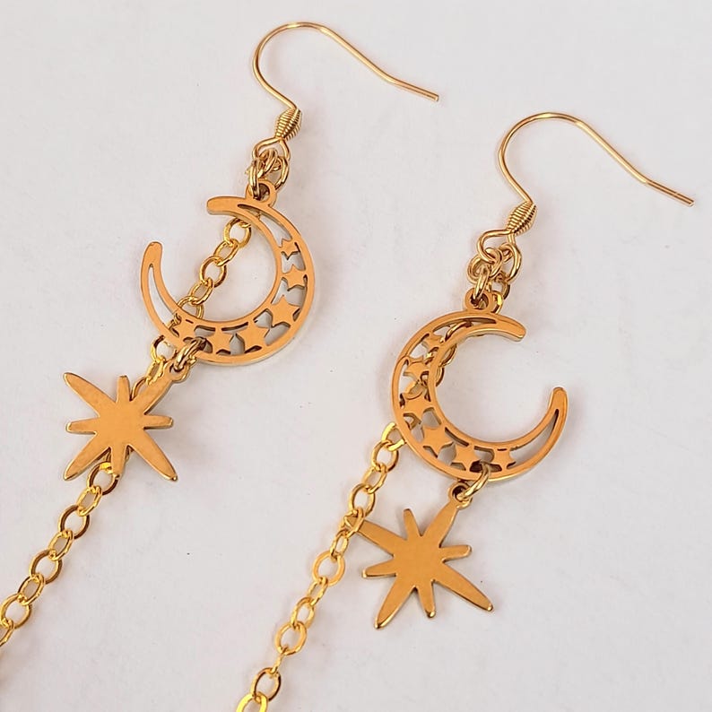 This image shows a more detailed close up of the crescent moon and north star charms attached to the earring hooks.