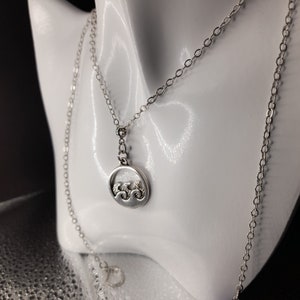May include: A silver chain necklace with a circular pendant featuring a wave design.
