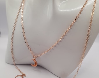 May include: A rose gold chain necklace with a crescent moon pendant and two small hoop charms.