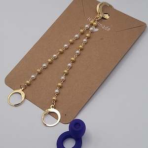 May include: Gold hoop earrings with a double strand of beads. One strand is gold and the other is white pearls. The earrings are on a brown card with the word "Handmade" written on it.