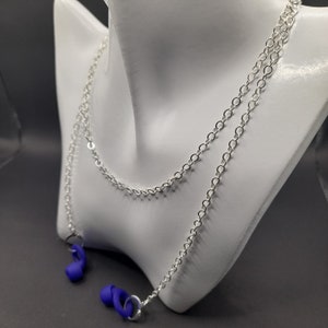 Könnte beinhalten: Eine silberne Kettenkette mit zwei daran befestigten blauen Silikon-Ohrhörerhaltern.