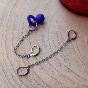May include: A pair of iridescent rainbow earrings with a blue silicone earplug on a chain.