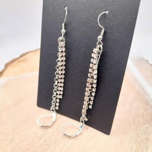 May include: A pair of silver dangle earrings with multiple strands of clear rhinestones.