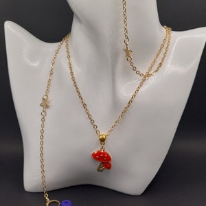 May include: Gold chain necklace with a red mushroom pendant and star charms. The necklace is layered and has a delicate chain.