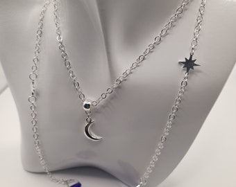 May include: A silver chain necklace with a crescent moon charm and a star charm. The necklace is attached to two blue silicone earbud holders.