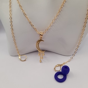 May include: A gold chain necklace with a crescent moon pendant and a dangling star design. The necklace comes with a pair of blue earrings.