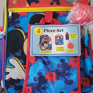 K&ouml;nnte beinhalten: Ein 4-teiliges Mickey Mouse-Schulsortiment mit einem 41 cm Rucksack, einer isolierten Lunchbox, einer Wasserflasche und einem weichen Ball. Der Rucksack ist blau mit einem Mickey Mouse-Muster und dem Text "Just So Awesome!" auf der Vorderseite. Die Lunchbox ist rot mit einem Mickey Mouse-Muster und dem Text "Awesome!" auf der Vorderseite. Die Wasserflasche ist blau und der weiche Ball ist rot.