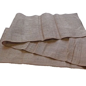 Puede incluir: Un rollo de tela de arpillera marrón con una costura en el centro. La tela está doblada por la mitad y tiene algunos pequeños agujeros.