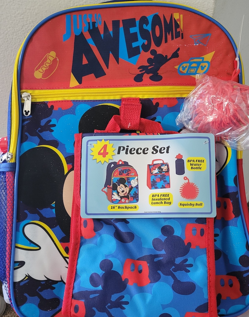 K&ouml;nnte beinhalten: Ein 4-teiliges Mickey Mouse-Schulsortiment mit einem 41 cm Rucksack, einer isolierten Lunchbox, einer Wasserflasche und einem weichen Ball. Der Rucksack ist blau mit einem Mickey Mouse-Muster und dem Text "Just So Awesome!" auf der Vorderseite. Die Lunchbox ist rot mit einem Mickey Mouse-Muster und dem Text "Awesome!" auf der Vorderseite. Die Wasserflasche ist blau und der weiche Ball ist rot.