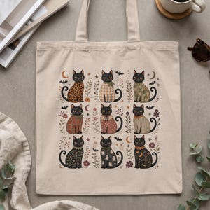 Tote bag with nine illustrated black cats in various Halloween-themed outfits.