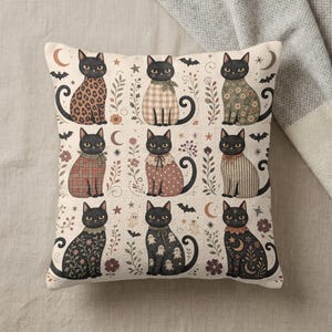 Halloween-themed pillow with nine black cats in various patterns and autumn floral accents.