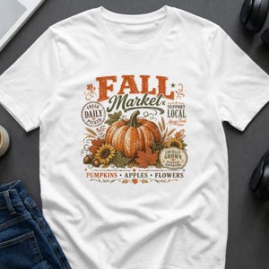 White T-shirt with vintage "Fall Market" graphic featuring a pumpkin, sunflowers, and autumn leaves.
