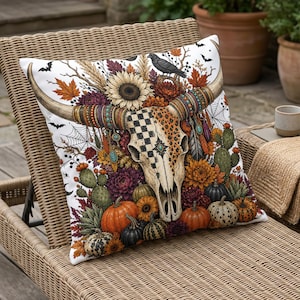 Skull with floral, pumpkin, and bat Halloween design on a throw pillow.