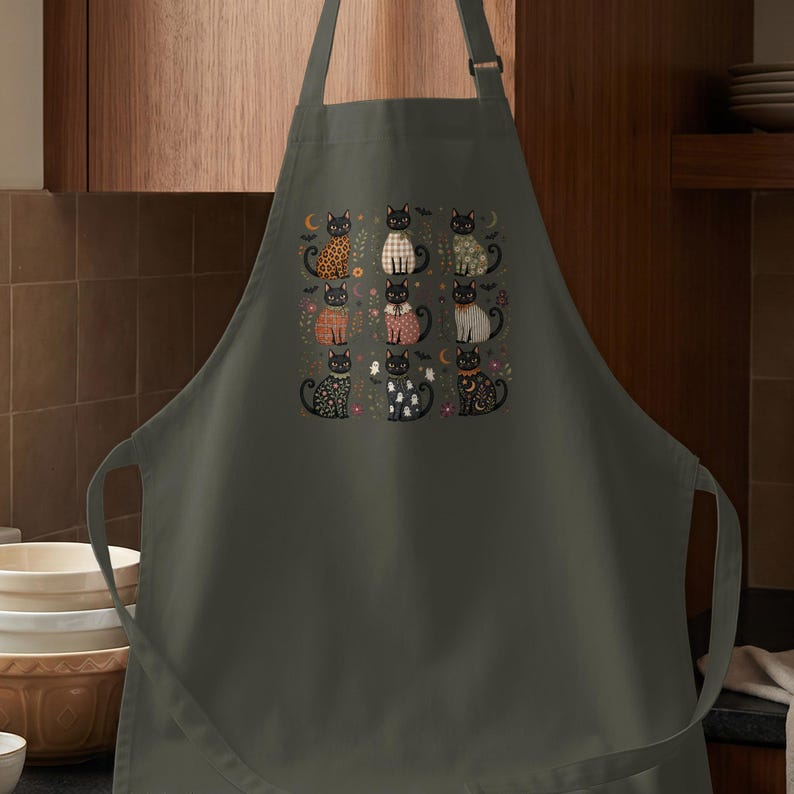 Apron with a graphic of nine stylized black cats and Halloween motifs.
