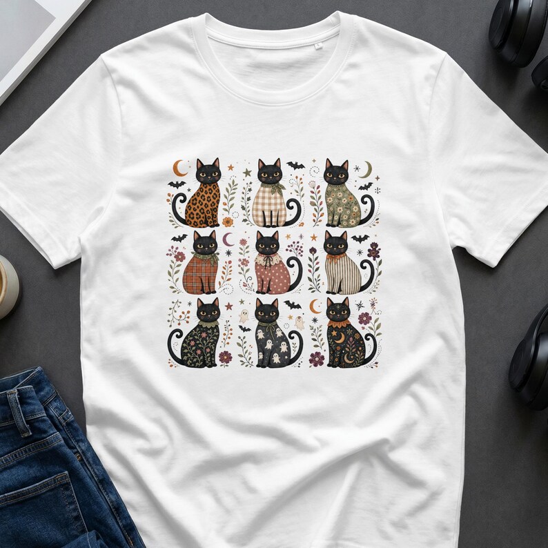White t-shirt with a grid of nine black cats with fall-themed patterns and Halloween motifs.