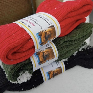 May include: Three pairs of socks in red, green, and black. The socks are made of alpaca wool and have a label that says "Super Soft Breathe + Stretchy, Alpaca Equestrian, Lough Rynn, 75% Alpaca 25% Wool, Alpaca Knee-High Socks".