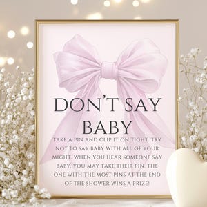 May include: A pink and white printable sign with a large pink bow and the text "DON'T SAY BABY" in black. The sign instructs guests to take a pin and clip it on tight, and to not say "baby" during the party. The person with the most pins at the end of the party wins a prize.