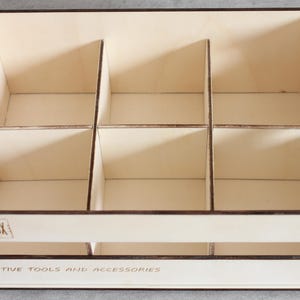 Könnte beinhalten: Eine Holzkiste mit neun Fächern, beschriftet mit "Stuffbox" und "Creative Tools and Accessories".