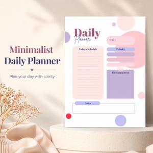 Puede incluir: Un planificador diario minimalista con fondo blanco, con secciones para programación, prioridades y notas. El diseño incorpora suaves acentos rosas y morados, con el texto "Daily Planner" y "Minimalist Daily Planner".