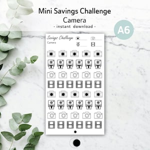 May include: A black and white printable sheet of stickers with a camera theme. The sheet includes multiple images of cameras, film reels, and numbers. The text "Savings Challenge" and "Camera" are at the top of the sheet. The text "A6" is in the top right corner of the sheet.