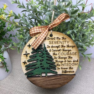 May include: A wooden ornament with a green pine tree design and the text "God Grant Me The Serenity To Accept The Things I Cannot Change. The Courage To Change The Things I Can. And The Wisdom To Know The Difference."