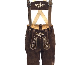 May include: Brown leather lederhosen with gold embroidery and suspenders. The suspenders are brown leather with a cream colored X-shaped strap.