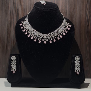 May include: A silver and pink crystal necklace and earrings set. The necklace features a delicate chain with a pendant of pink crystals and silver accents. The earrings are drop earrings with a similar design.