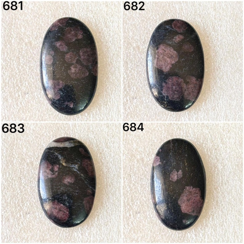 May include: Four oval-shaped gemstones with a dark, glossy surface. Each stone has a base color of black with irregular patches of deep red or purple. The gemstones are numbered 681, 682, 683, and 684.