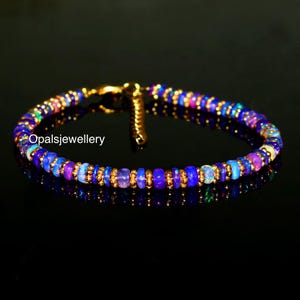 Peut inclure: Un bracelet délicat en or avec une fermeture à fermoir, composé d'un mélange de petites perles d'opale irisées rondes dans des tons de bleu, violet et rose.