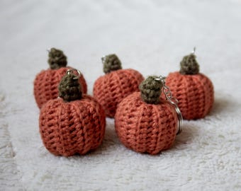 May include: Five crocheted pumpkin keychains in shades of orange and green. The keychains are made with a textured stitch and have a small loop for attaching keys.