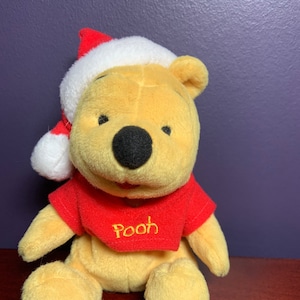 Mattel Winnie the Pooh, Santa Pooh Christmas Plush Bear.  Wearing a Santa Hat and a “Pooh” Red Shirt.