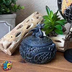 Puede incluir: Caja de alhajas de dragón negro con un intrincado diseño de nudos celtas. La tapa presenta una escultura de dragón detallada.