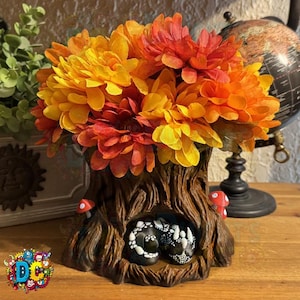 May include: A decorative tree trunk vase filled with orange, yellow, and red flowers. The brown vase has a hollowed-out section with two black skulls. Two red and white mushroom accents are on the vase.