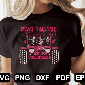 May include: A black t-shirt with a graphic of three skeletons in a pink jeep. The skeletons are holding musical instruments and the text "Dead Inside - But It's Valentine's" is printed below the jeep.