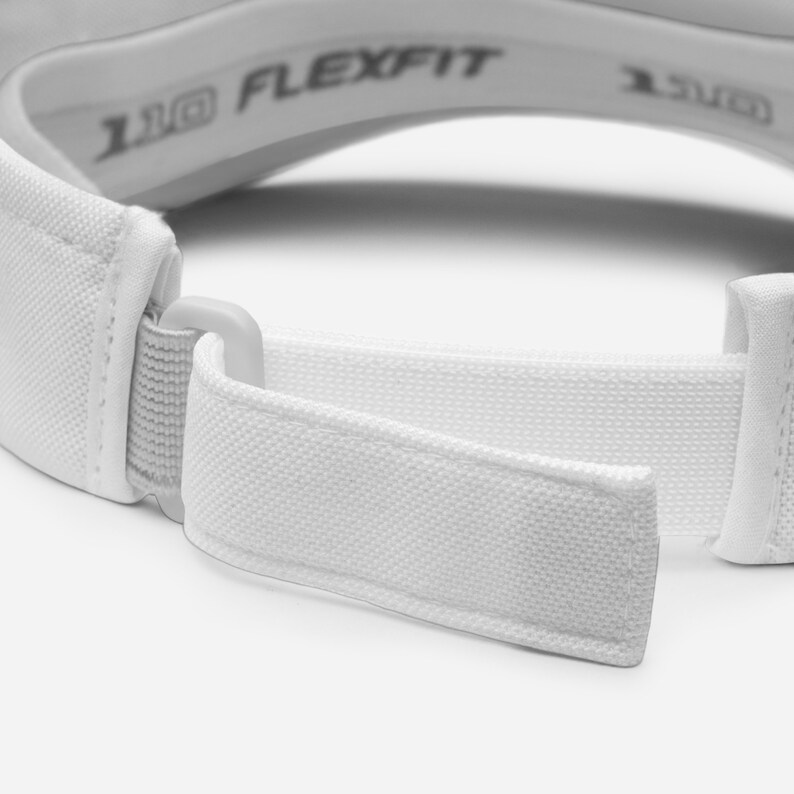 K&ouml;nnte beinhalten: Nahaufnahme eines wei&szlig;en Visiers mit gebogener Krempe und verstellbarem Riemen. Auf der Innenseite des Visiers ist der Text "110 FLEXFIT" aufgedruckt. Der verstellbare Riemen besteht aus wei&szlig;em, leinwandartigem Material.