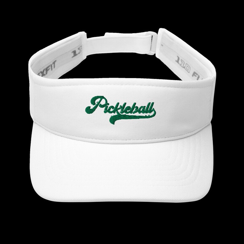 K&ouml;nnte beinhalten: Wei&szlig;es Visier mit dem Wort "Pickleball" in gr&uuml;ner Schrift auf der Vorderseite gestickt. Das Visier hat einen gebogenen Schirm und einen verstellbaren Riemen. Die Marke Flexfit ist auf der Seite sichtbar.