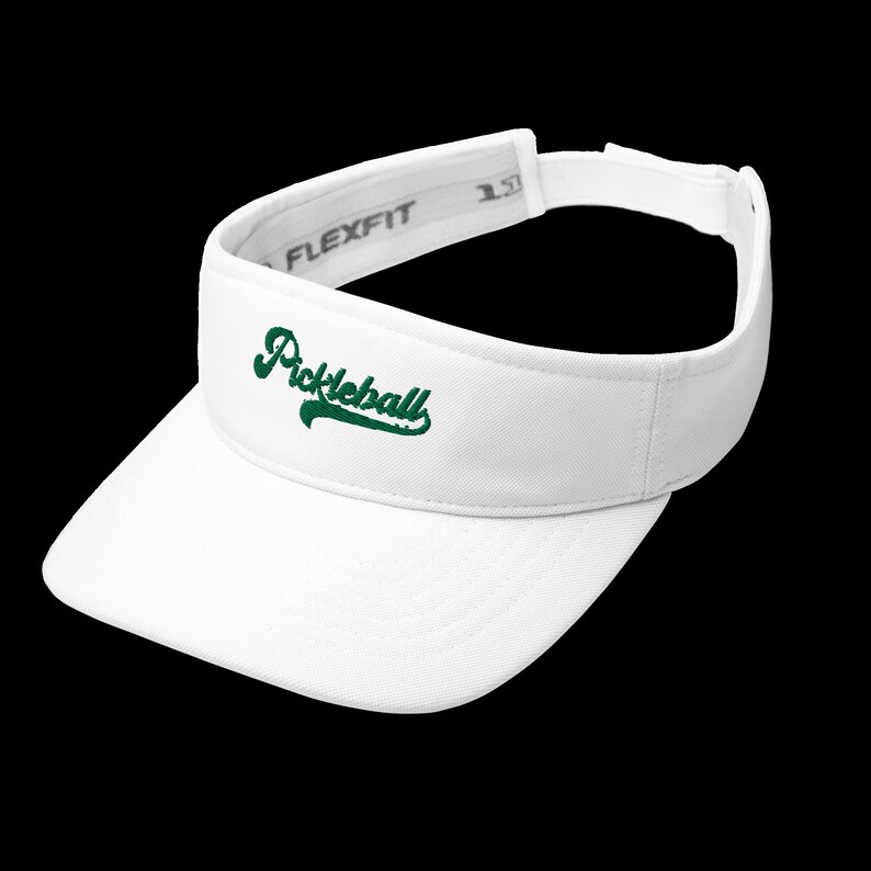 K&ouml;nnte beinhalten: Wei&szlig;es Flexfit-Visier mit dem Wort "Pickleball" in gr&uuml;ner Schrift auf der Vorderseite gestickt. Das Visier hat einen gebogenen Schirm und einen verstellbaren Riemen.
