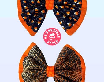 May include: Reversible Halloween hair bows. One side has a black background with candy corn, the other a black spiderweb design. Both sides have an orange border and centre knot.